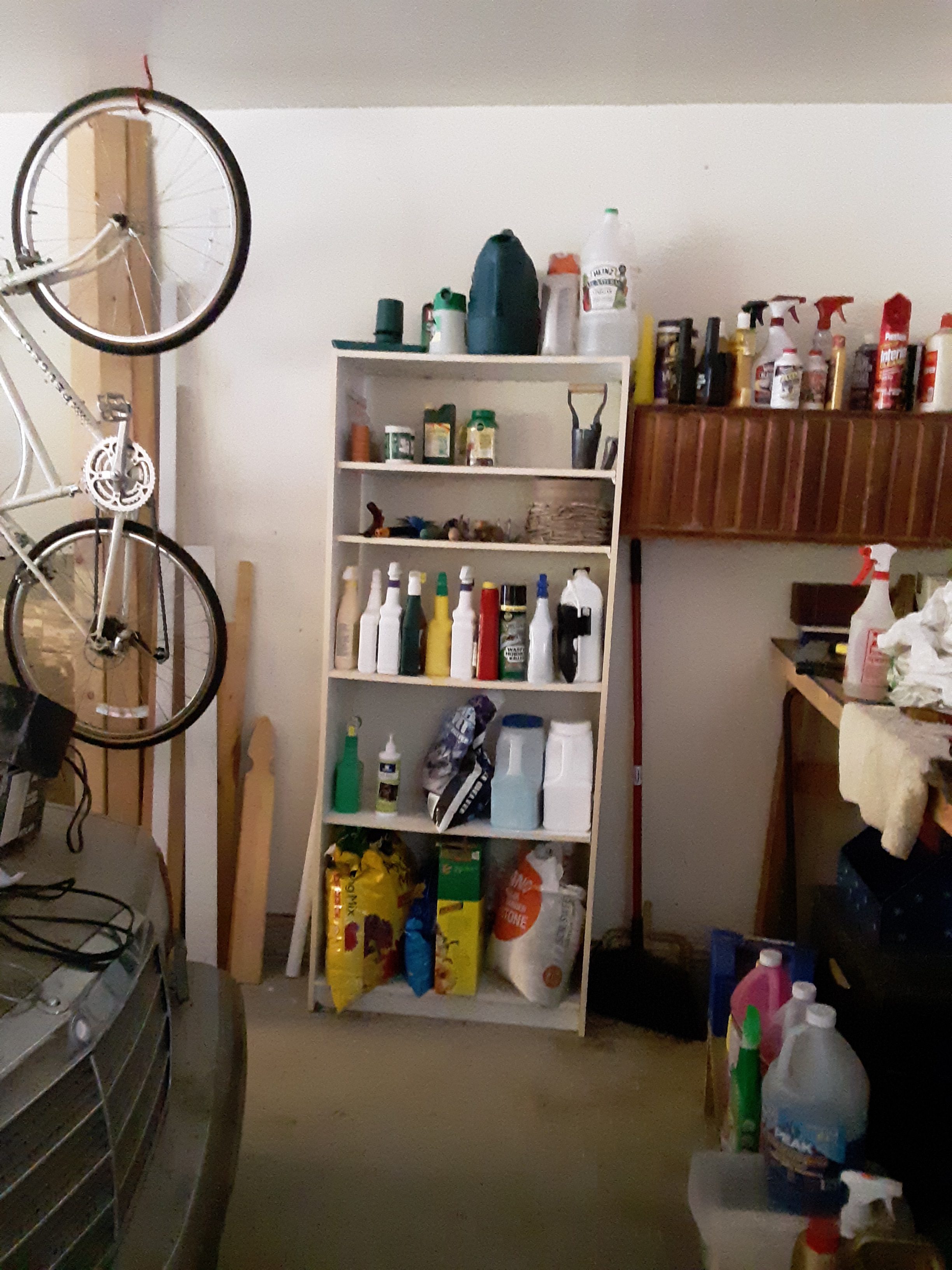 Garage shelves, now organized, holding gardening items, grass seed, tools