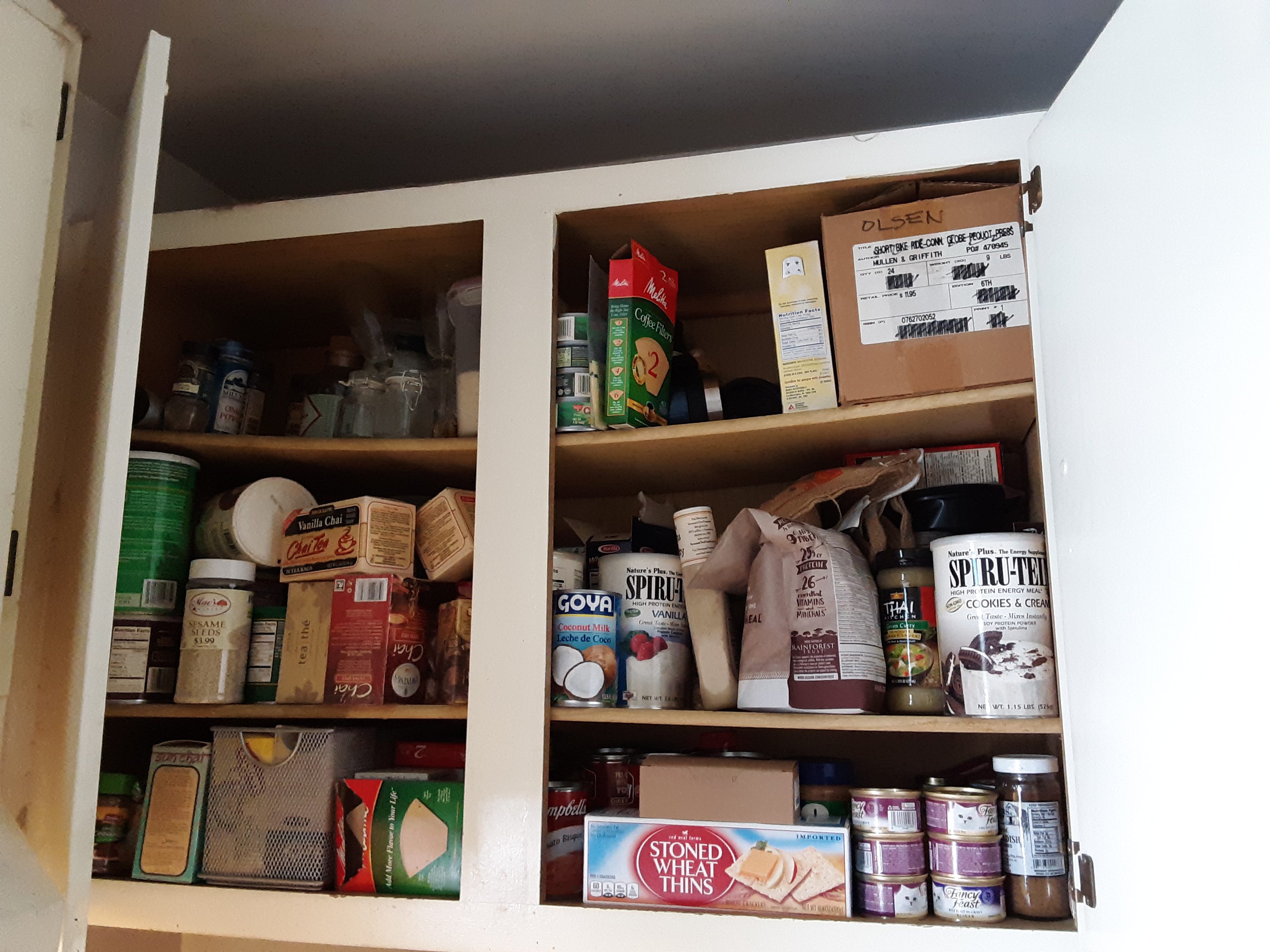 A very full kitchen cupboard before organizing it.