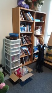 The tall bookcase before we cleared its clutter and straightened its books